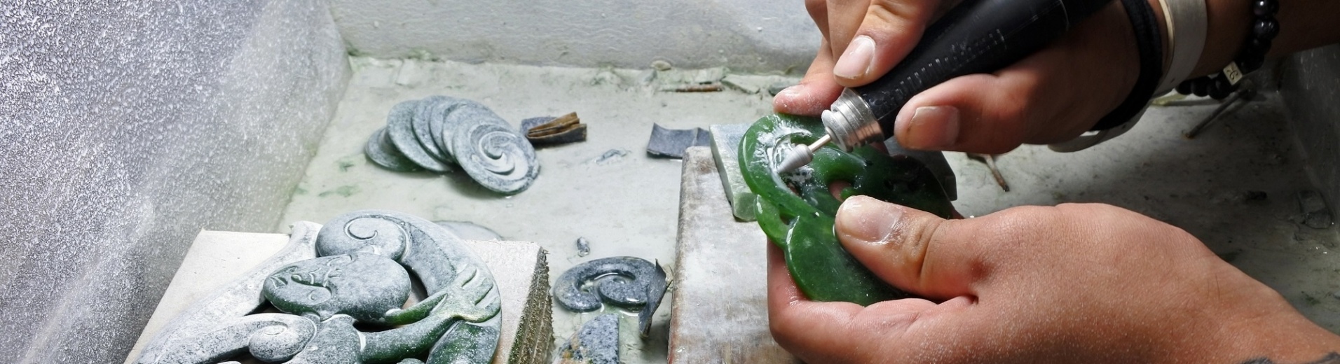 des mains en train de façonner une pierre de jade en forme moarie