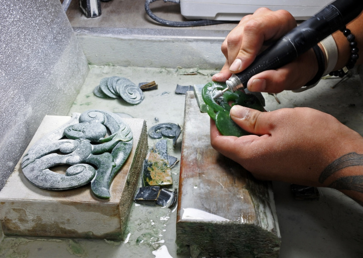 des mains en train de façonner une pierre de jade en forme moarie