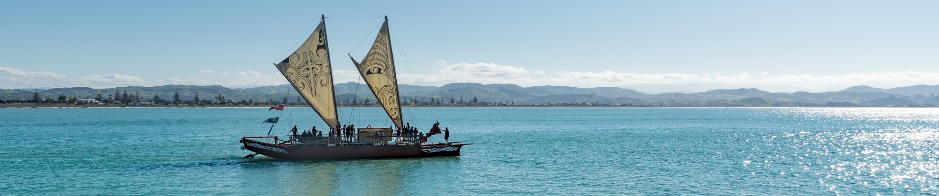 canoe maori sur l'eau avec des voiles